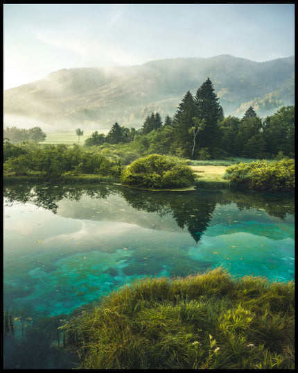 Ein Poster von einem See der von Büschen, Bäumen, Strand und Bergen umgeben ist.