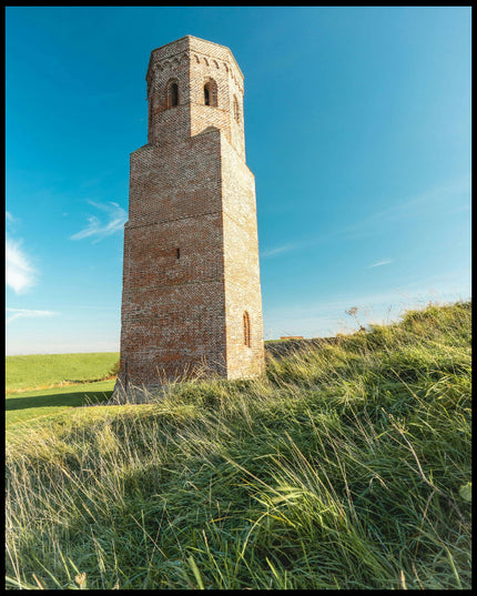 Ein Poster von einem steinernen Turm auf einer grünen, hügeligen Wiese.