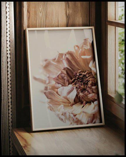 Ein gerahmtes Poster von einer Nahaufnahme einer vertrockneten Blume, vor einem Fenster an die Wand angelehnt