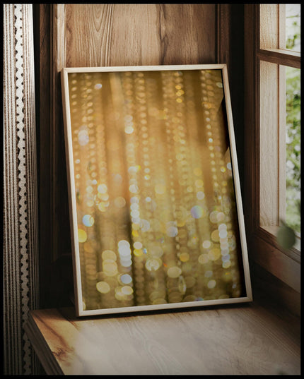 Ein gerahmtes Poster von goldenem Bokeh mit funkelnden Lichtreflexen, vor einem Fenster an die Wand angelehnt